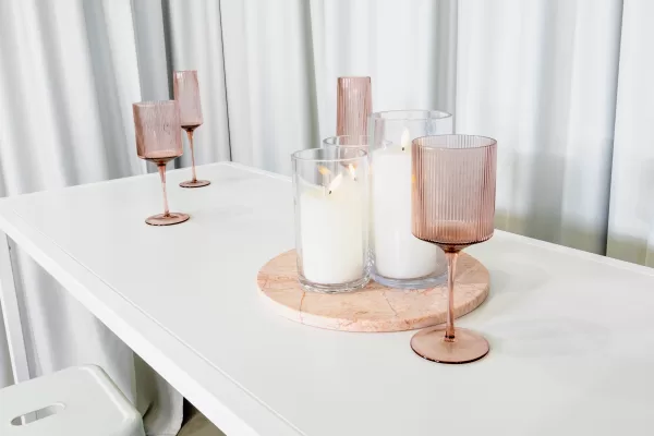 candles and pink glassware placed on a white rectangular table